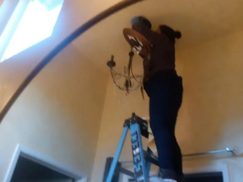 Electrician installing a chandelier in a Harriman residence